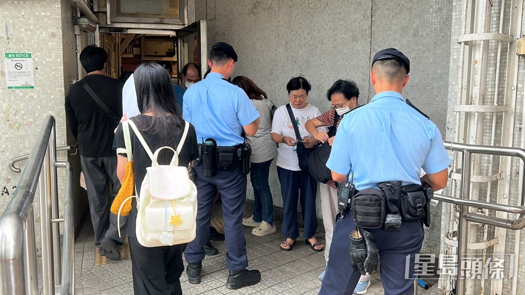 警察機動部隊在大廈出入口向居民登記並詢問是否住5號或7號室。