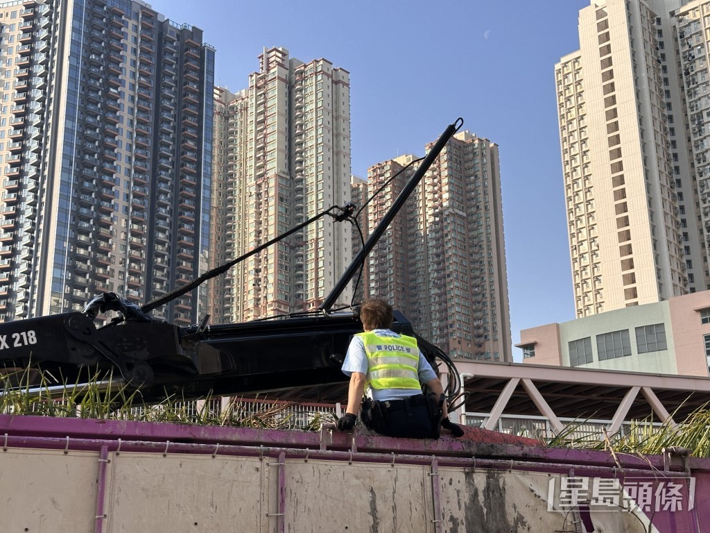 有交通警爬上吊車車斗上，協助將吊臂與架空電纜分開。梁國峰攝