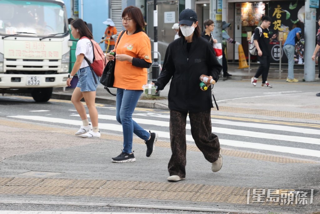 梁靖琪在醫院外現身，一身黑衫Cap帽低調打扮的她拿着飲品及小食過馬路。