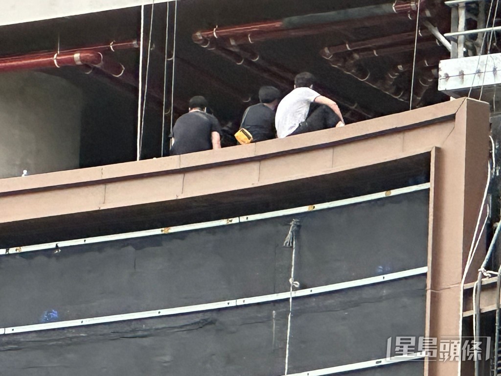 工人危坐五樓平台邊緣。 工人危坐五樓平台邊緣。