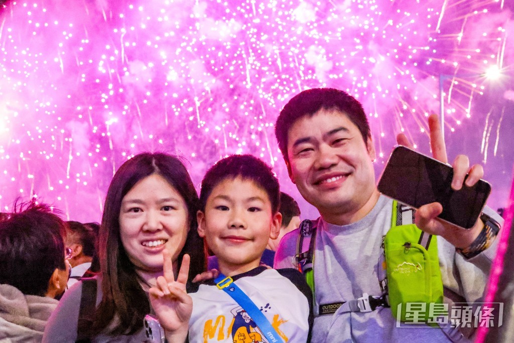 不少人舉起手機捕捉煙花的精彩畫面,亦有人與煙花合照「打卡」。 不少人舉起手機捕捉煙花的精彩畫面,亦有人與煙花合照「打卡」。