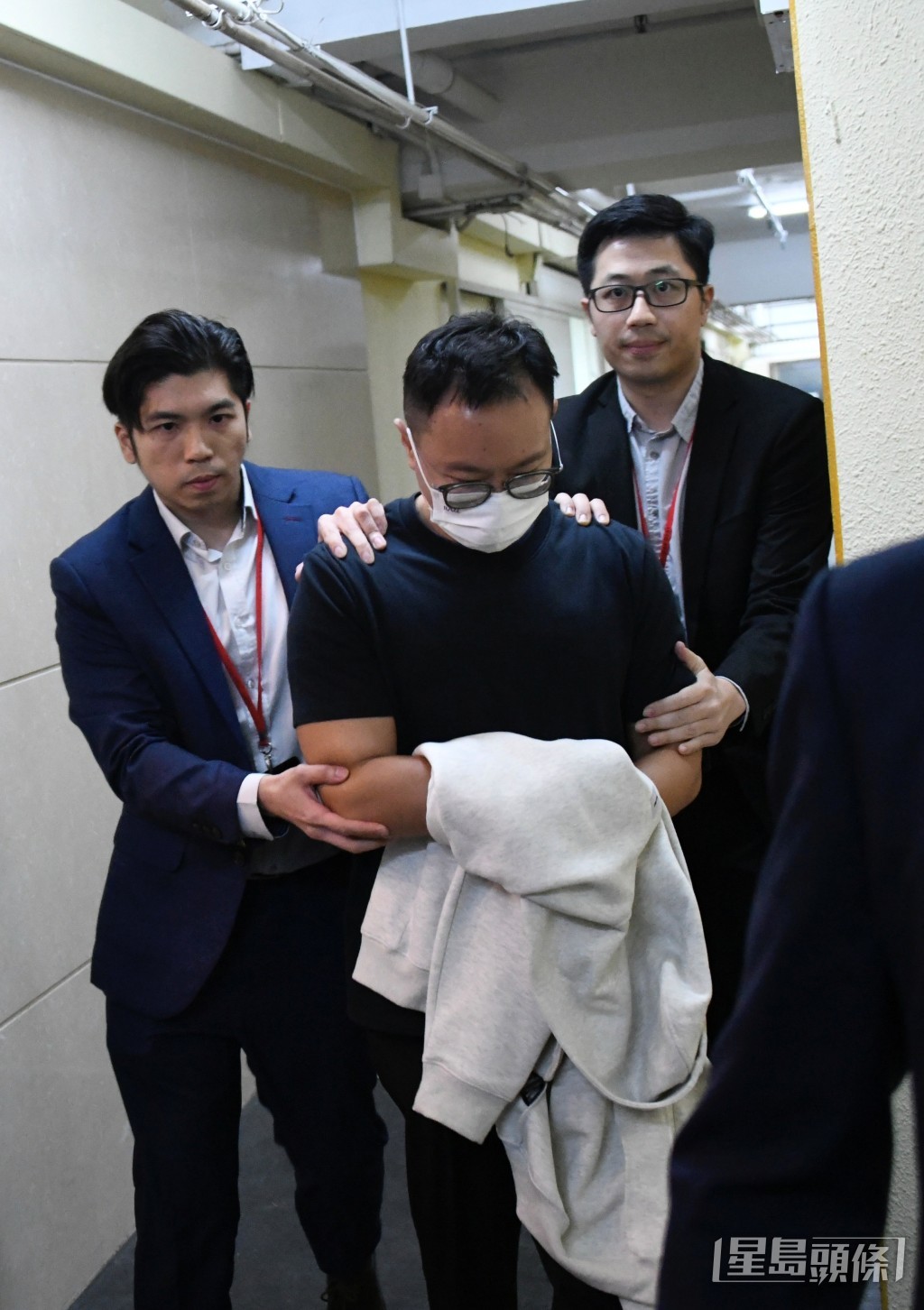 另一名男子雙手包裹外套被押到九龍灣辦公室調查。楊偉亨攝