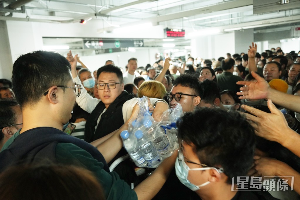 职员向排队人员派发樽装水。吴艳玲摄