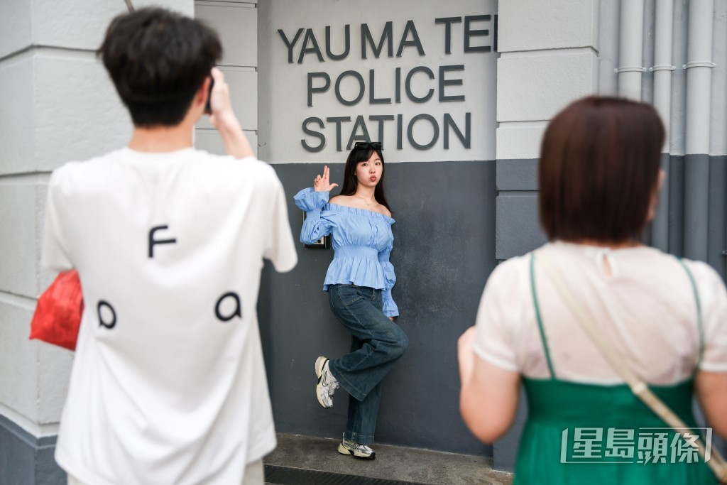 不少遊客以「持槍」手勢在「油麻地警署」招牌下拍照。