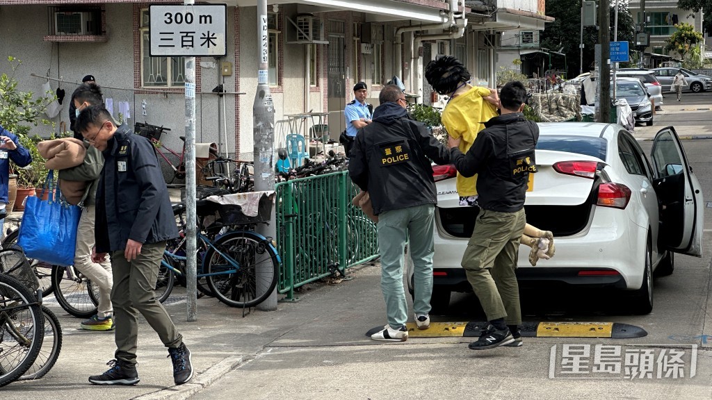 探員帶同代表死者的假人公仔到場，進入涉案村屋單位。梁國峰攝