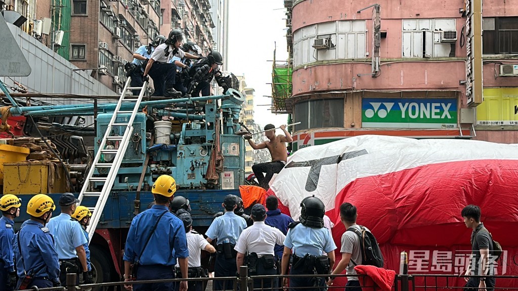 赤膊男在吊臂車上攀爬。劉漢權攝