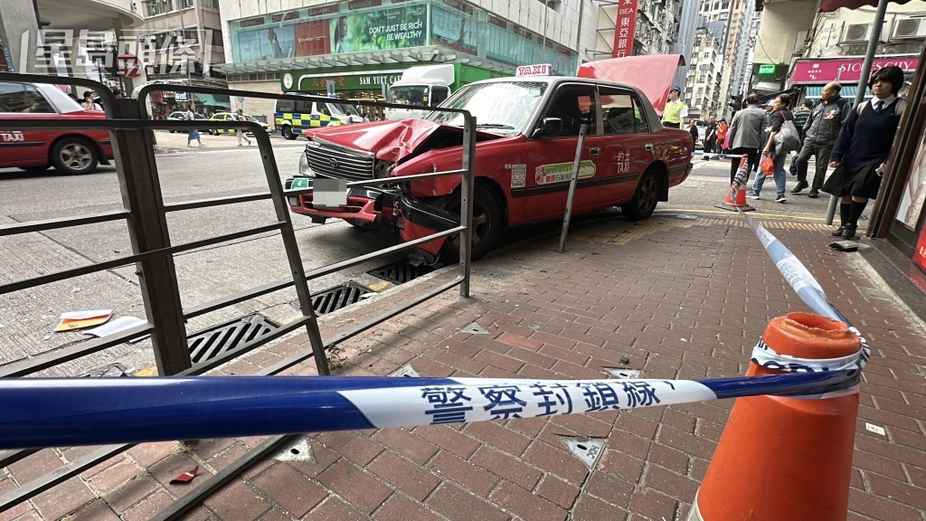 的士失控撞欄，並撞倒一名婦人，將她夾在路邊鐵欄和車身之間。劉漢權攝