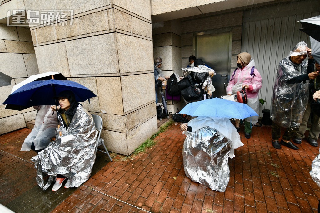 巿民冒着寒雨排隊等候旁聽，有人披上錫紙保暖。盧江球攝