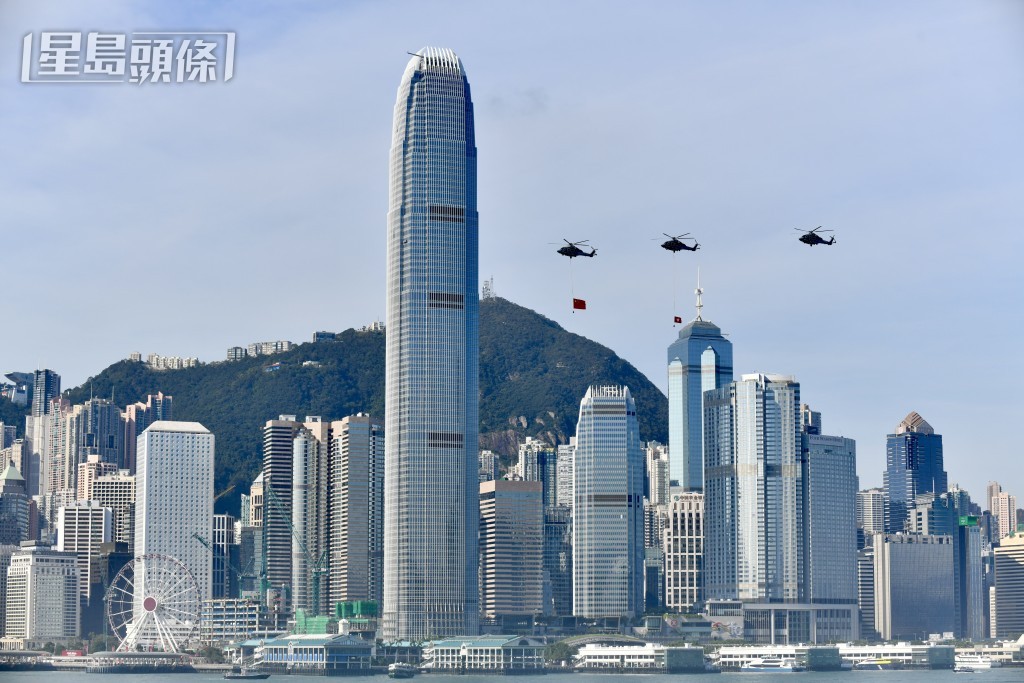 掛有國旗及區旗的政府飛行服務隊直升機同時飛進維港。盧江球攝
