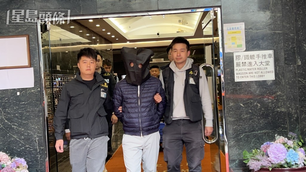 被捕人黑布蒙頭，由警員帶走。蔡楚輝攝