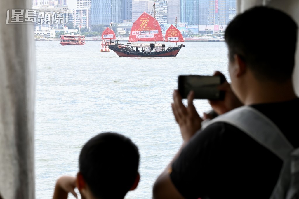 不少旅客舉起手機拍攝維港兩岸景色。