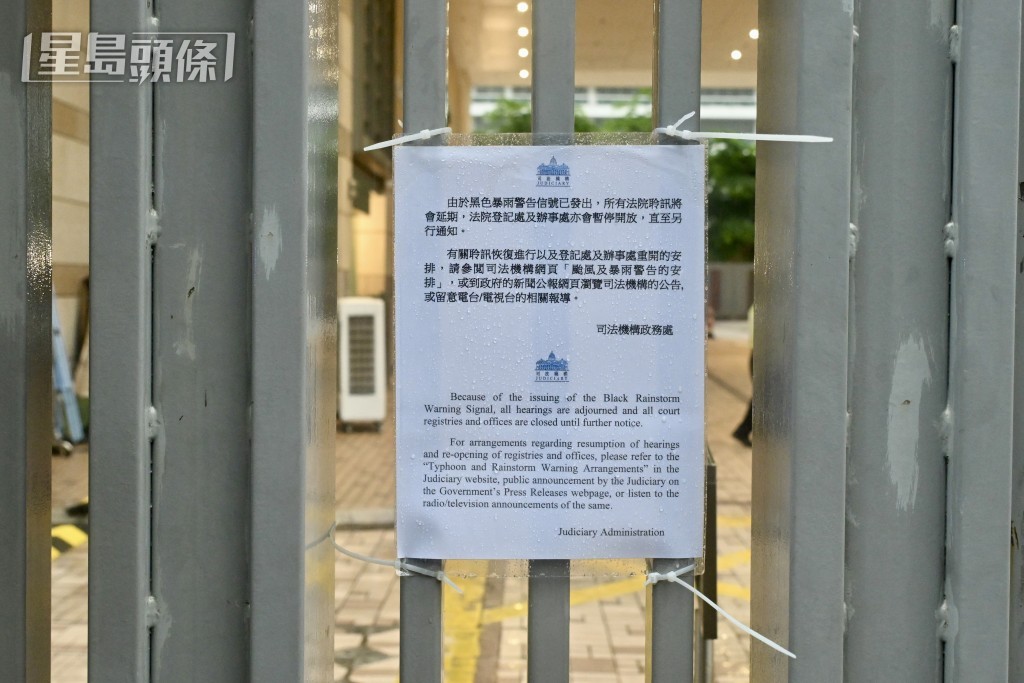 法庭保安於閘外張貼黑色暴雨警告生效告示。劉駿軒攝