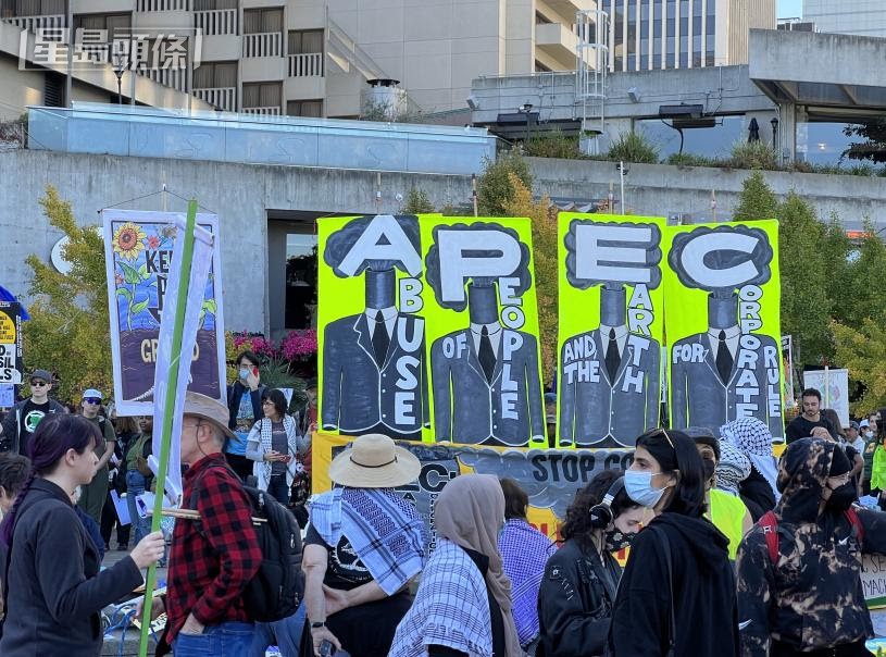 现场人士高举的四个大型标语牌以“APEC”四个英文大字缩写，批评企业私利伤害人类和地球。记者彭诗乔摄