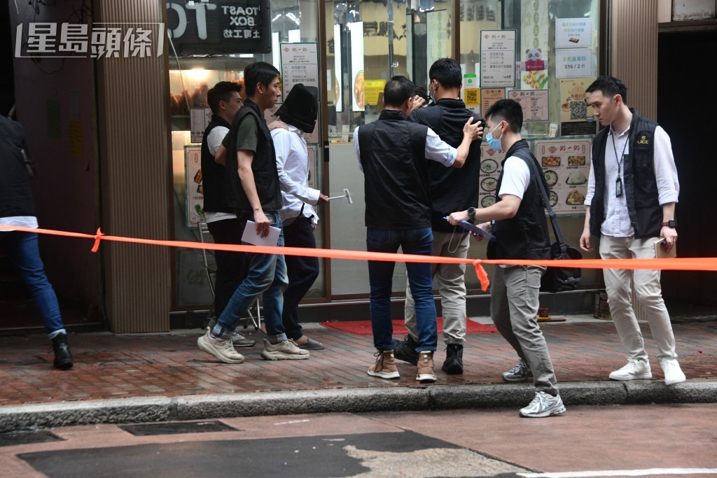 被告巫泰峯(白衣蒙頭)被捕後被帶返現場重組案情。資料圖片 被告巫泰峯(白衣蒙頭)被捕後被帶返現場重組案情。資料圖片