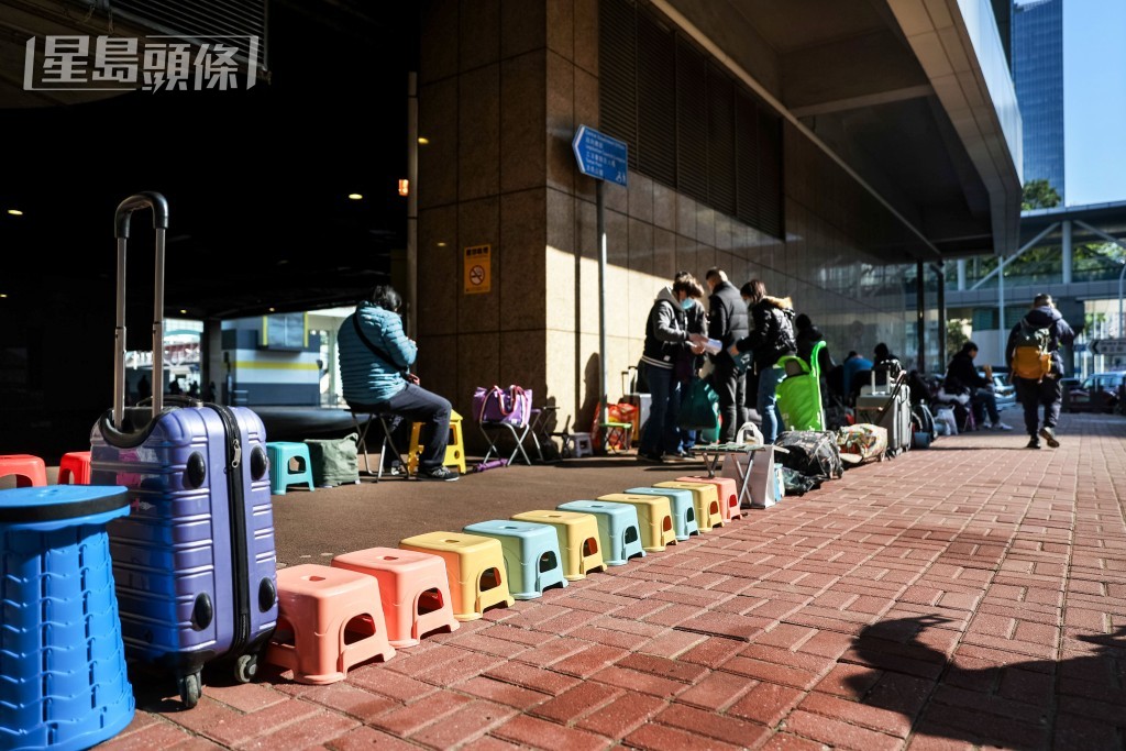 有人用空凳、雨傘、行李箱等物霸位代為排隊。
