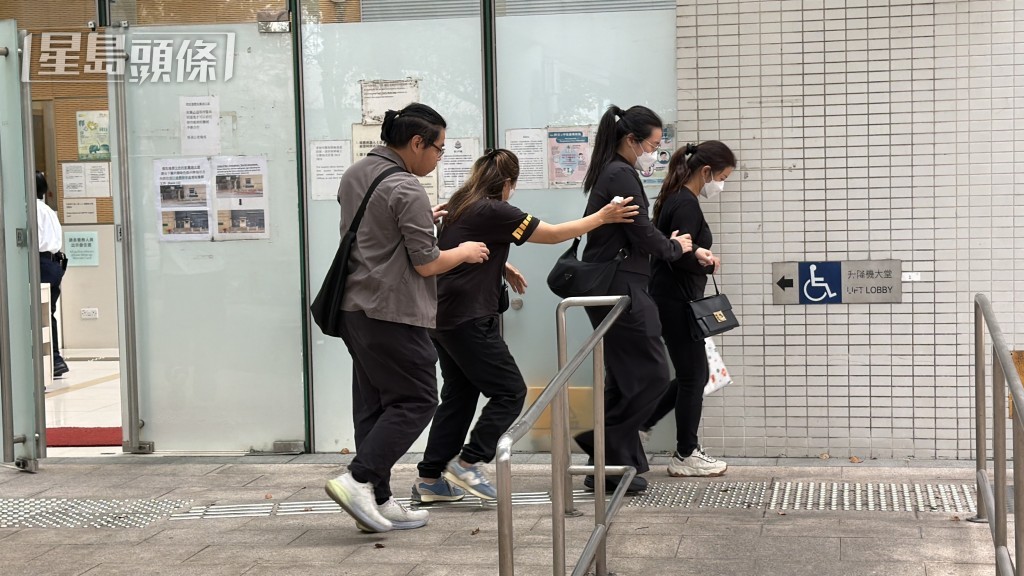 死者家屬在工權會代表（左）陪同下，到葵涌殮房認領遺體。