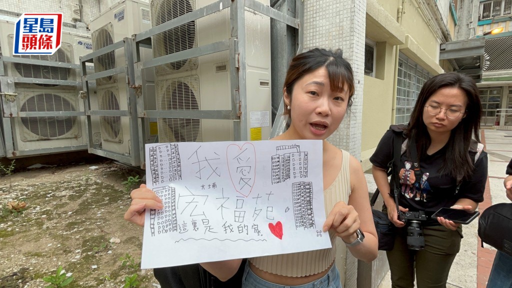 范女士帶著兒子有關宏福苑的畫作上樓。楊偉亨攝