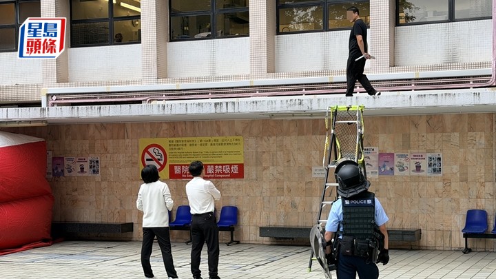 伊利沙伯醫院男子危站簷蓬，手持角鐵與警對峙。梁國峰攝