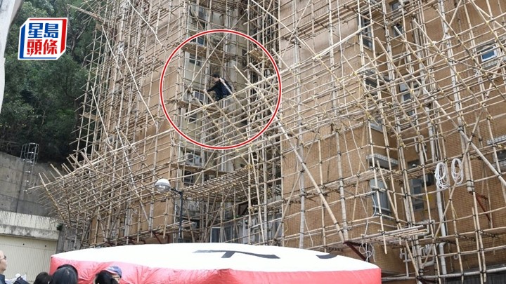 工人爬棚架追薪，消防張開氣墊。楊偉亨攝