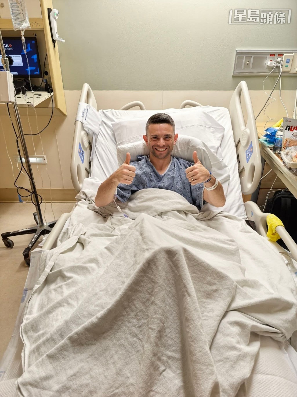 李寶利 (圖) 今天在其社交平台親自發放近照，相中他在醫院床上，面上展示其招牌燦爛笑容，雙手高舉拇指報平安。相片來源：李寶利Facebook