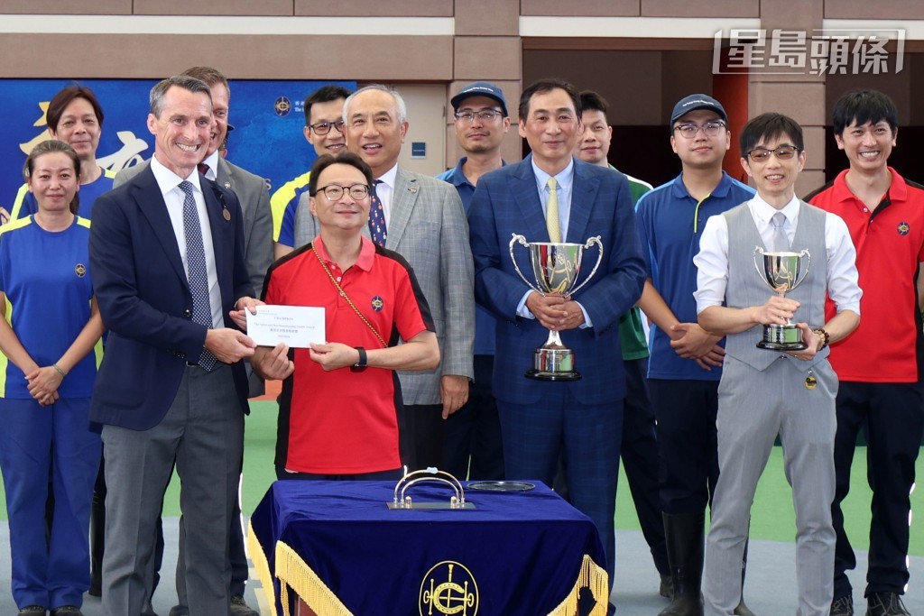 香港賽馬會賽馬日營運、跑道及賽馬設施部主管暨職業安全委員會主席(賽事執行部)夏俊思(左),將「最安全及整潔馬房獎」的馬房獎項頒予鄭俊偉馬房的員工代表。 香港賽馬會賽馬日營運、跑道及賽馬設施部主管暨職業安全委員會主席(賽事執行部)夏俊思(左),將「最安全及整潔馬房獎」的馬房獎項頒予鄭俊偉馬房的員工代表。