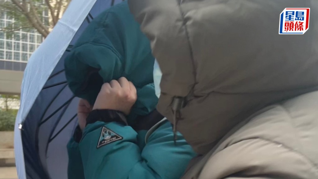 被告黃潔瑩（左）在同伴掩護下離開法庭。廖凱霖攝