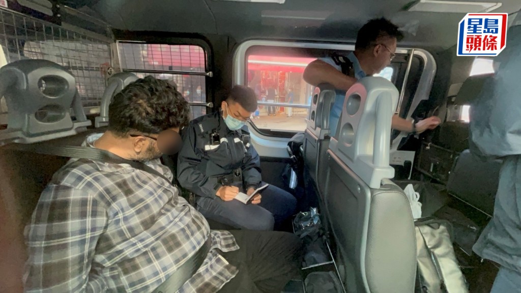 其中一名非華裔人蛇被帶上警車。楊偉亨攝