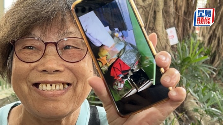 婆婆展示檢回部分個人物品的照片，表現開心。蔡楚輝攝