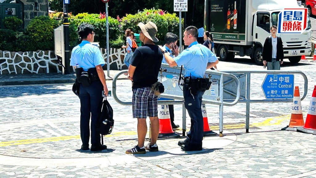 馬來西亞男子被帶上警車助查，警員手持其背囊。蔡楚輝攝