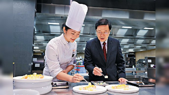 ■香港國際美食大獎25歲以下「海鮮組」銀牌得獎學員黃湘，就教特首點擺盤藝術，為作品嚟個「終極點綴」。